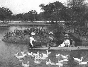 Photograph of women in small rowboat feeding ducks