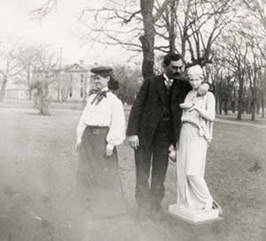 Photograph of man with his arm around a sculpture as his female companion looks away