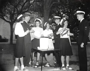Photograph of young women in uniforms serving beverages to several men