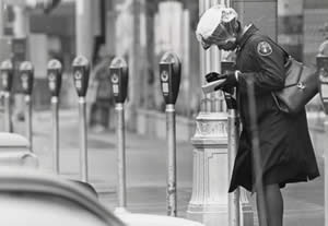 Photograph of meter maid writing a parking ticket